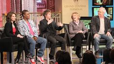 four people sitting on chairs talking to each other