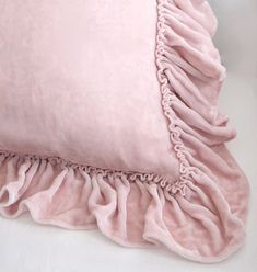 a pink pillow with ruffled edges on a white surface