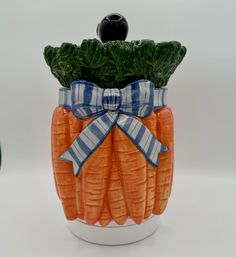 a ceramic vase with carrots wrapped in blue and white ribbon