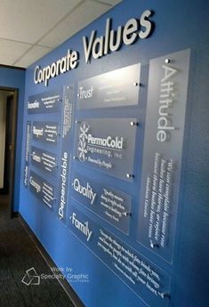 a blue wall that has some glass signs on it and the words corporate value are written in different languages