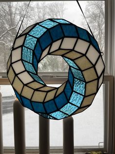 a blue and white circular stained glass window hanging from a pole in front of a window