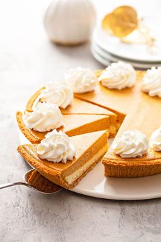 a cheesecake with whipped cream is on a plate next to other desserts and utensils