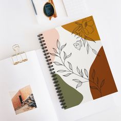 an open spiral notebook on top of a desk next to a pair of eyeglasses