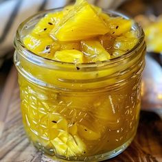 a jar filled with sliced pineapples on top of a wooden table