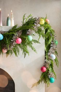 a christmas garland with candles and ornaments on the mantle