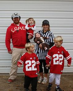 a family dressed up in football uniforms posing for a photo with their baby and toddler