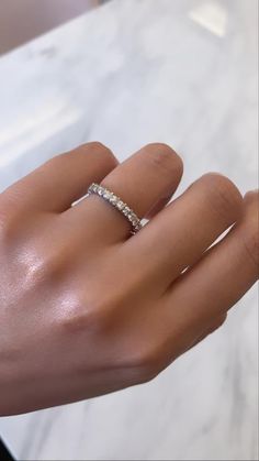 a woman's hand with a diamond ring on top of her left hand,