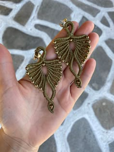 a hand holding two pairs of earrings in it's palm, with gold beads on them