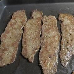 four pieces of meat cooking in a frying pan