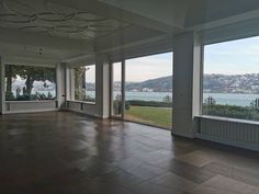 an empty room with large windows overlooking the water