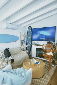 a woman sitting in a living room next to a surfboard