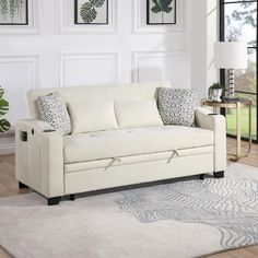 a white couch sitting on top of a rug in a living room next to a window