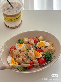 a white bowl filled with food next to a cup of coffee on top of a table