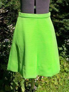 "This vintage 1970s \"Flip Skirt\" has been custom-made of easy care spring green acrylic double-knit fabric. This was the miracle fabric of the time. It was called a \"Flip Skirt\" because it has a slight flare out at the bottom and seems to flip as you walk. This skirt has a waistband and a nylon zipper on the left side. A hook waist closure closed the waistband. It has seams center front and center back with 2 back darts for shaping. Actual color is not as neon green as in the photo. Its a ni Retro Green A-line Skirt, Fitted A-line Green Skirt, Vintage Stretch Green Bottoms, Vintage Green Summer Skirt, Vintage Green Skirt For Summer, Vintage Green Skirt For Spring, Vintage Fitted Green Skirt, Vintage Green Full Skirt Bottoms, Vintage Green Full Skirt