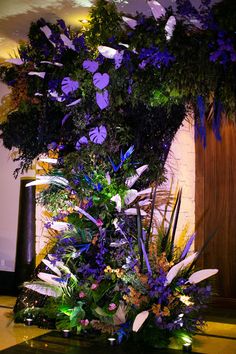 an arrangement of purple flowers and greenery on display