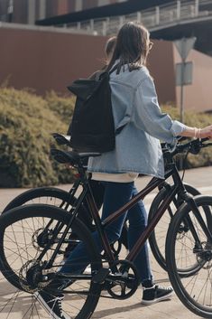 the woman is riding her bike down the street with a back pack on it's back