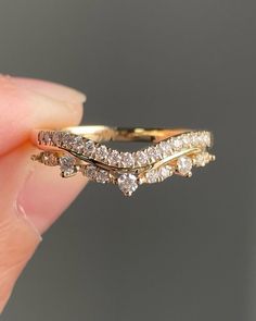 a person holding a gold ring with three diamonds on it's sides and the middle finger