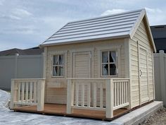 a small wooden house sitting on top of a cement ground next to a fence and building