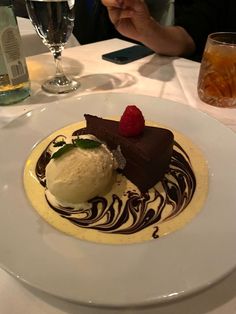 a white plate topped with a piece of cake and ice cream covered in chocolate sauce