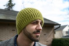 a man wearing a green knitted hat in front of a house