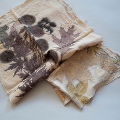 two pieces of cloth with leaves on them sitting next to each other in front of a white background