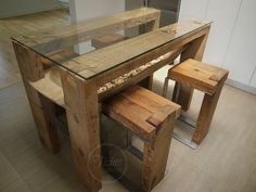 a wooden table with two stools and a glass top on the floor in a kitchen