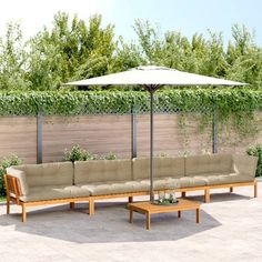 a couch and table with an umbrella in the middle of a patio area next to a fence