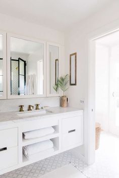 a white bathroom with two sinks and mirrors