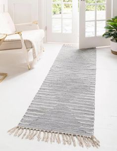 a white and gray rug with tassels on the floor in front of a door