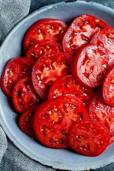 a bowl filled with sliced tomatoes on top of a table