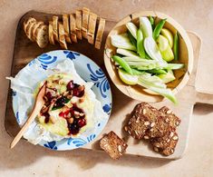 an assortment of food is displayed on a cutting board next to bread and other foods