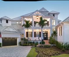 a large white house with palm trees in the front yard