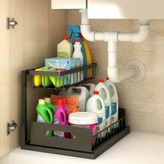 a bathroom sink filled with lots of cleaning supplies next to a toilet paper dispenser