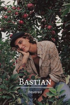 a young man sitting in an apple tree with his hand on his chin and looking at the camera