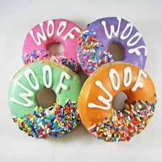 four donuts with sprinkles that say woof woof on them