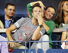 a man and woman sitting next to each other in the stands at a baseball game