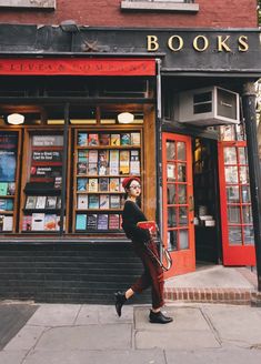 a woman walking down the sidewalk in front of a book store