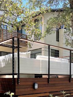 a bed sitting on top of a wooden platform next to a white building and trees