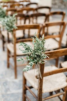 rows of wooden chairs with greenery tied to them