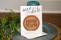 save the date magnets are on top of a plate with greenery in the background