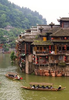 two boats floating on top of a river next to tall buildings with balconies