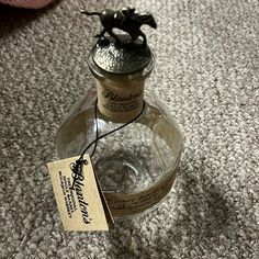 an empty bottle sitting on the floor with a tag hanging from it's top