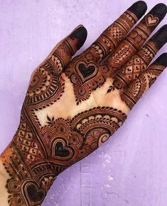 the hand is decorated with henna and hearts on it's palm, which has been