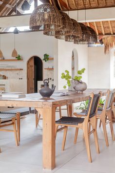 a wooden table with chairs and vases on it