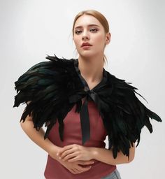 a woman in a red top with black feathers on her shoulders and an open collar