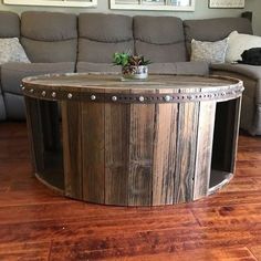 a wooden table sitting on top of a hard wood floor next to a gray couch