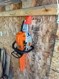 an orange and black chainsaw hanging on the side of a wall