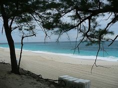 an air conditioner sitting on top of a sandy beach next to the ocean and trees