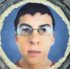 a cake with a photo of a man wearing glasses on it's side and frosting around the edges