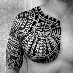 a black and white photo of a man's chest with an intricate tattoo design